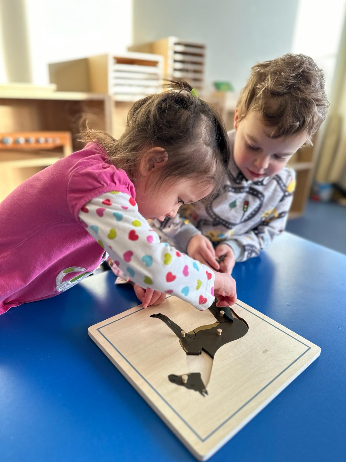 A boy and a girl working together to complete a wooden puzzle of a horse.